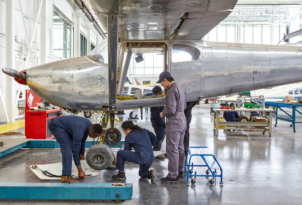 Three mechanics working on an airplane indoors